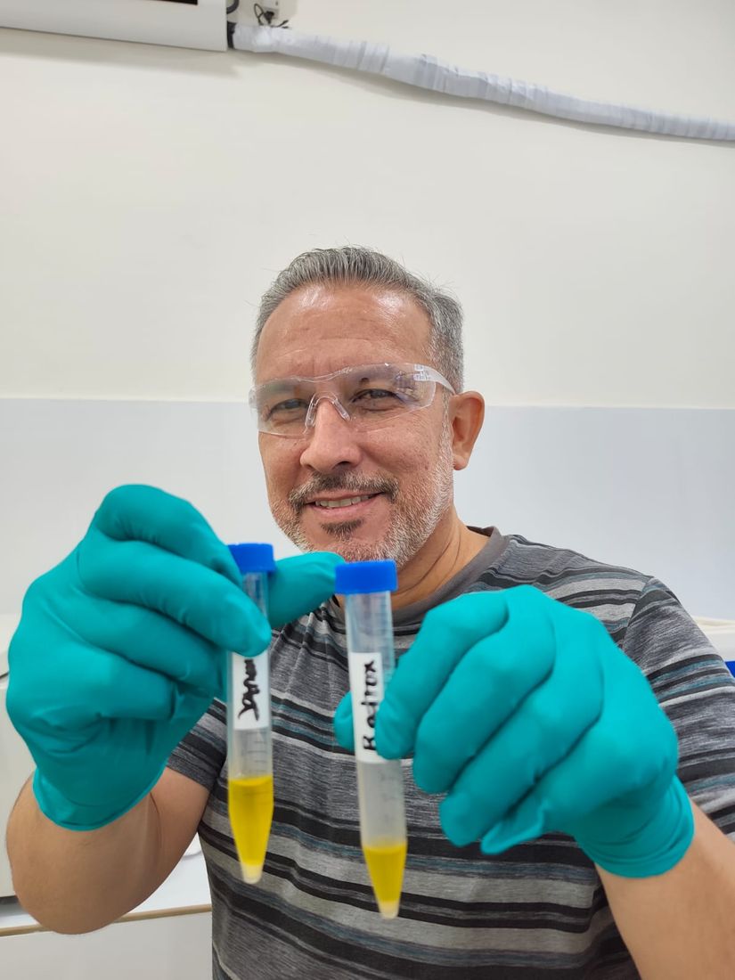 Technician in safety glasses and nitrile gloves holding two labelled tubes of freshly extracted venom.